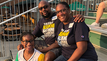 Two alumni and thier daughter sitting and smiling at a Columbus alumni chapter event