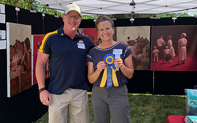 Victoria Arendt holding her second palce ribbion in front of her Art on The Mall booth