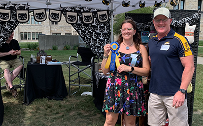 Carrie Hawkins holding her second palce ribbion in front of her Art on The Mall booth